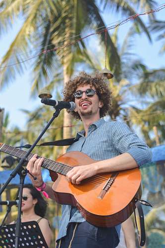 leisure activities selective focus photography of man performing on stage playing guitar musical instrument
